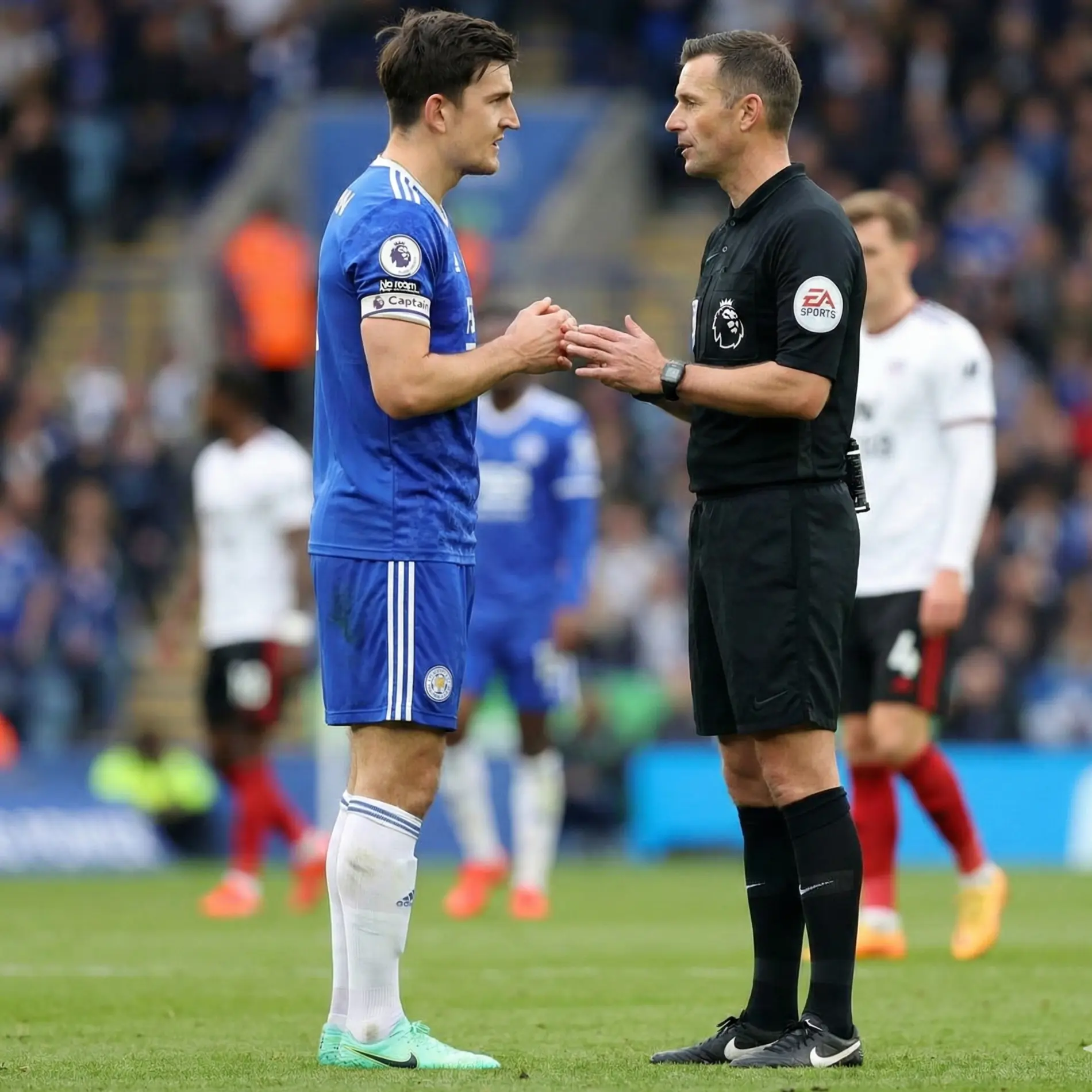 Football captain talking calmly to referee during match stoppage